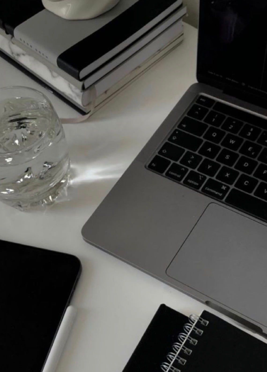 A laptop and glass of water on a desk during content planning